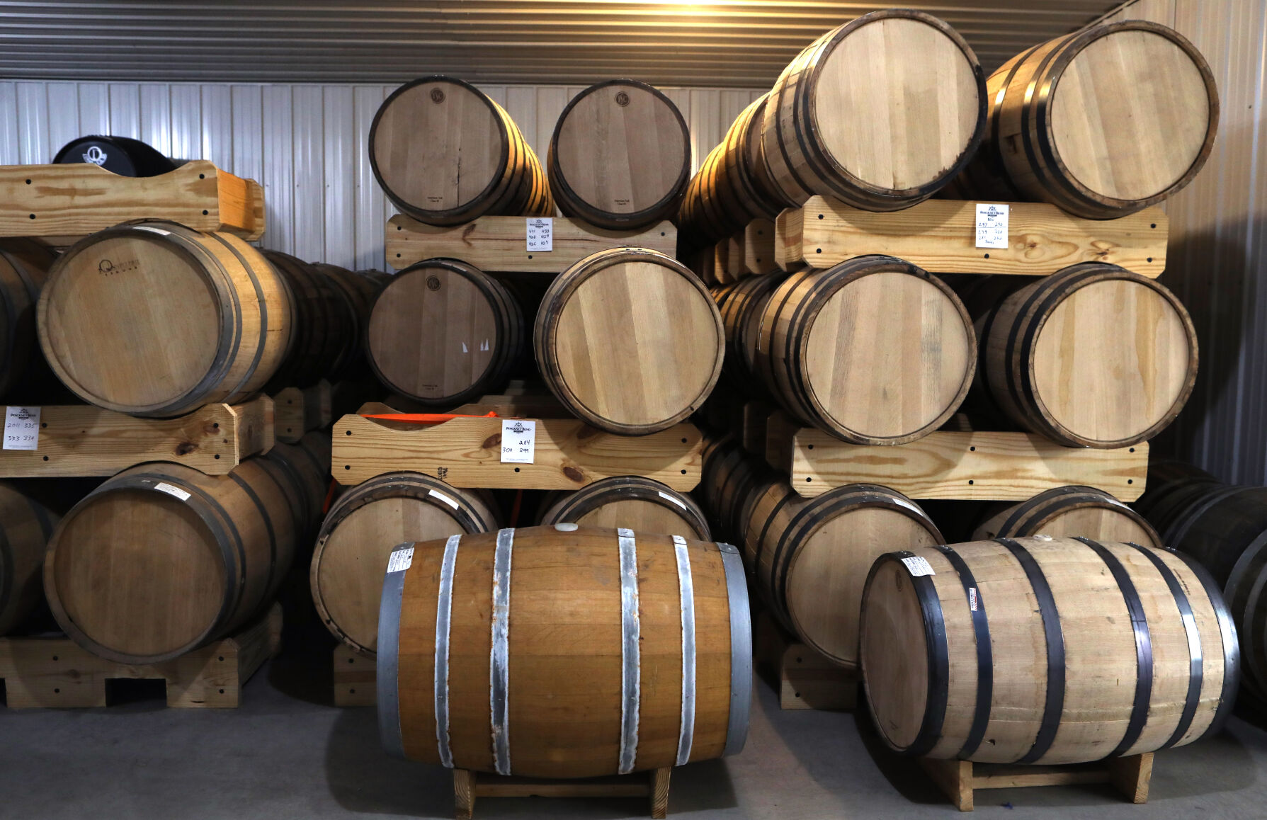 Barrels of aging alcohol sit in a building